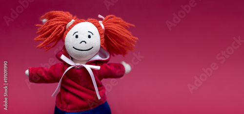 Little red riding hood smiling and cute female or girl rag or fabric doll with pigtails isolated on a red background