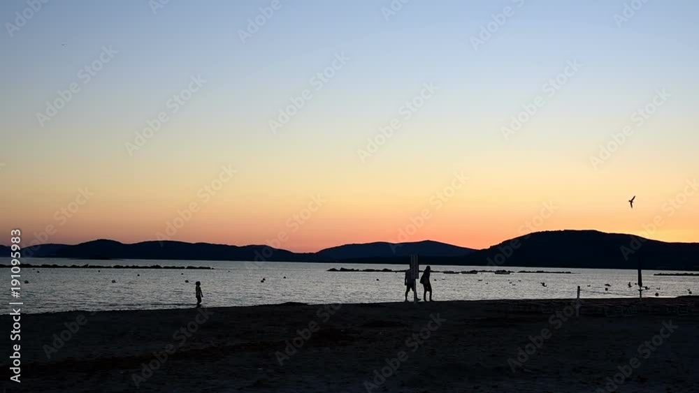 People walking by the sea at sunset. Sardinia, Italy People walking by the sea at sunset. Sardinia, Italy