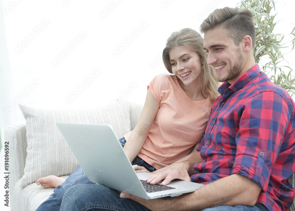 smiling young couple with laptop sitting on the couch smiling young couple with laptop sitting on the couch