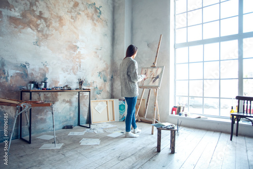 Young woman artist painting at home creative standing drawing photo