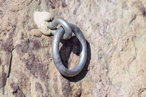 Detail of steel bolt anchor eye in sandstone rock. The end knot of steel rope. Climbers path © steuccio79
