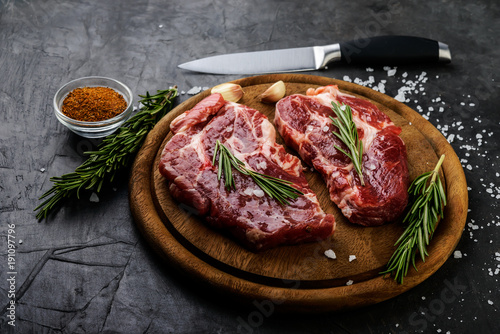 Raw meat with rosemary and spices in a board on black background