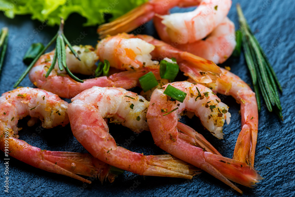 Cooked shrimps, prawns with seasonings on dark stone background Cooked shrimps, prawns with seasonings on dark stone background