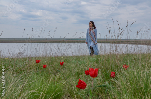 young woman among wild red tulips on the lake shore in grasslands Manych-Gudilo, Kalmykia © ssmalomuzh