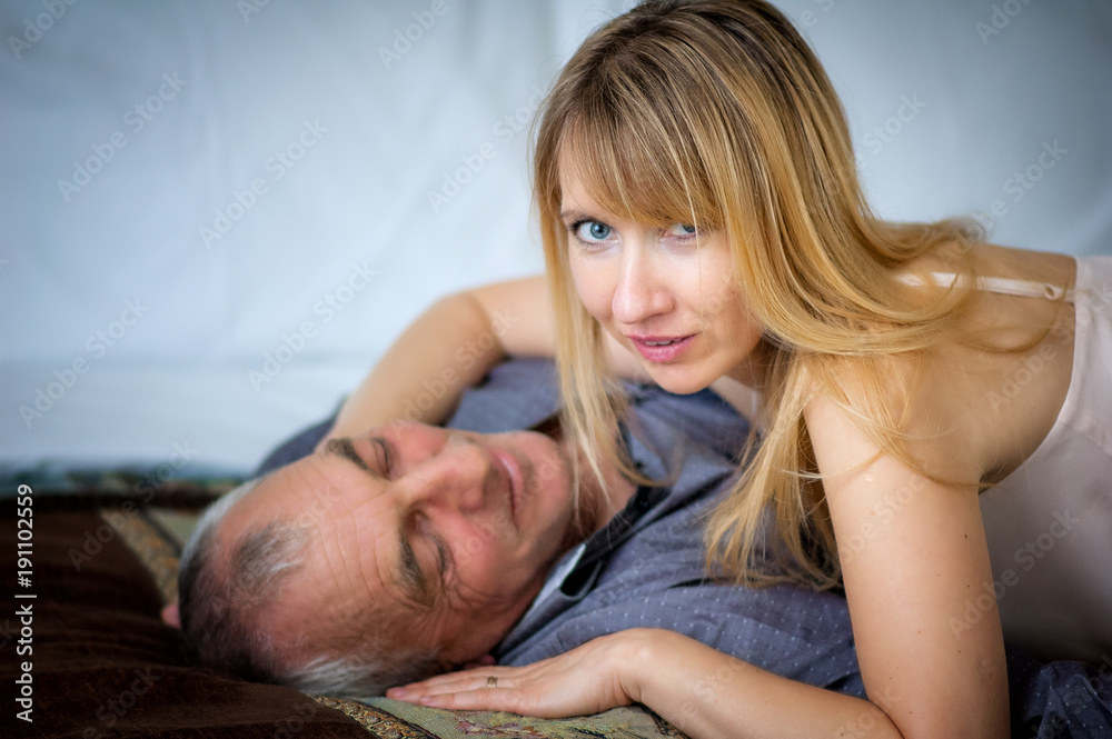 Beautiful Blond-Haired Woman in Sexy Lingerie Hugging Her Senior Husband  Lying in Bed. Couple with Age Difference. Stock-Foto | Adobe Stock