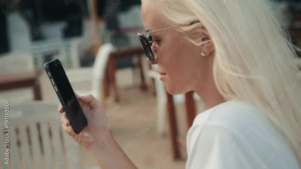 girl drinks juice and checks the phone in the hotel cafe on vacation with a view of the sea and the beach. Portrait on a bright sunny day. girl drinks juice and checks the phone in the hotel cafe on vacation with a view of the sea and the beach. Portrait on a bright sunny day.