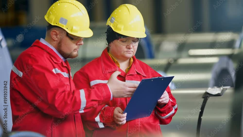 Two workers in production plant as team discussing, industrial scene in background Two workers in production plant as team discussing, industrial scene in background