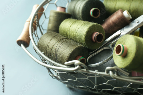 Metal basket with color sewing threads on grey background, closeup