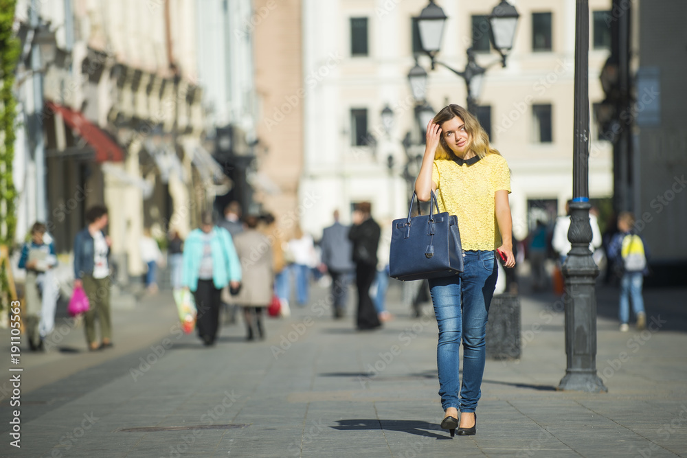 Young beautiful pretty girl walking along the street with phone in hand Young beautiful pretty girl walking along the street with phone in hand