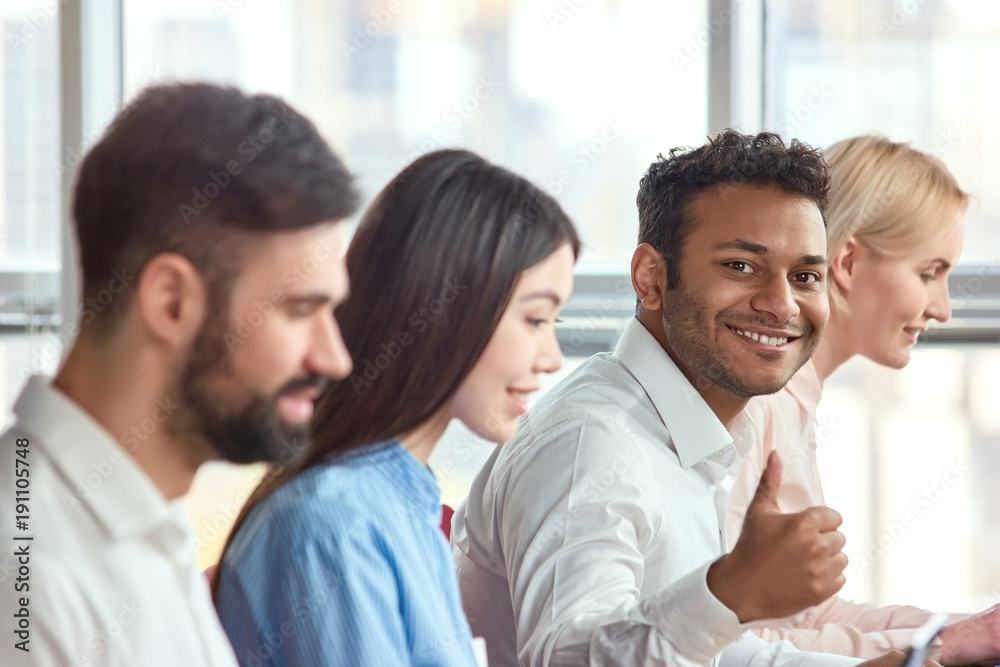 Sitting young indian black man showing thumb up. Young adult stubbled black man showing approval gesture, thumb up. Sitting young indian black man showing thumb up. Young adult stubbled black man showing approval gesture, thumb up.