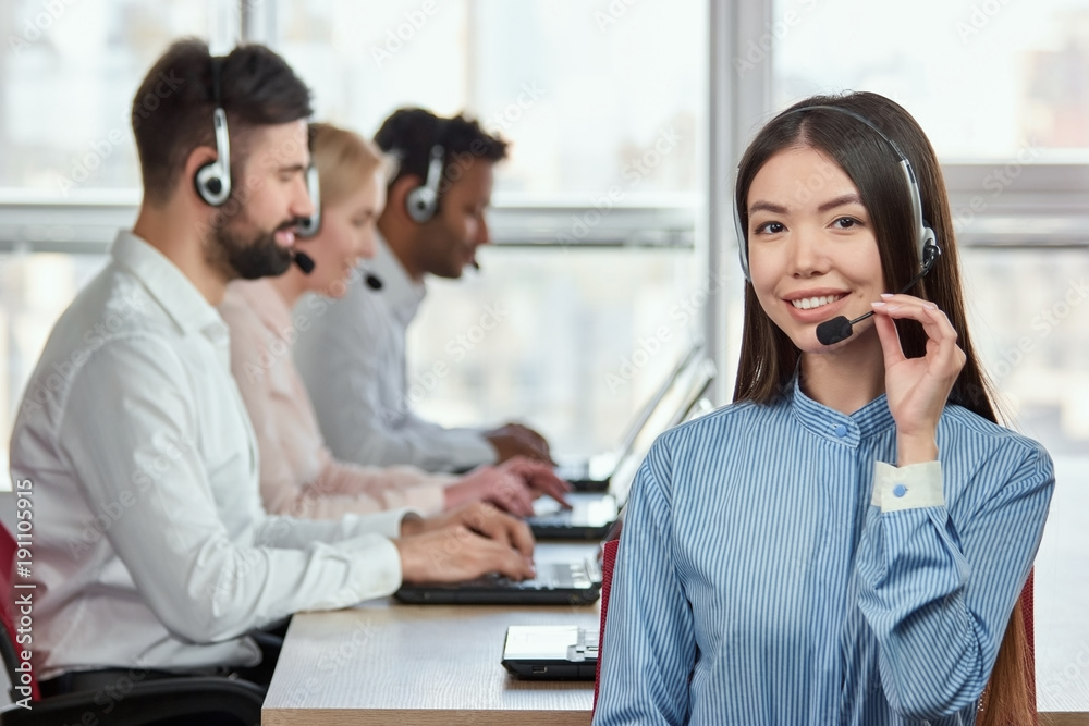 Korean girl wearing headset. Portrait of smiling girl adjusting headset in bright office. Korean girl wearing headset. Portrait of smiling girl adjusting headset in bright office.