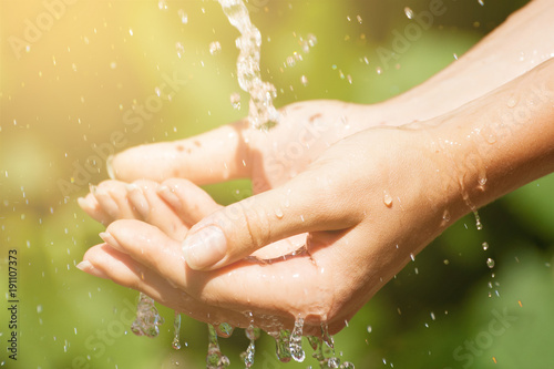 Woman washing hand outdoors. Natural drinking water in the palm. Young hands with water splash, selective focus