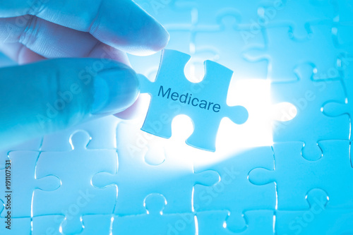 Health Care Concept. Doctor holding a jigsaw puzzle with medicare word. photo