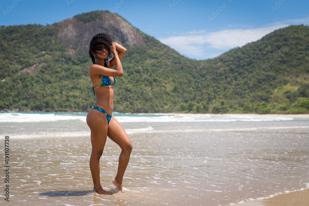 Young Attractive Woman in Bikini Posing in a Beach with Mountains in Background
