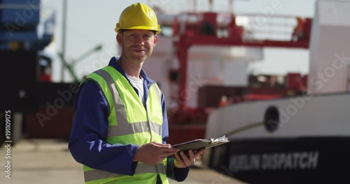 A dock worker standing at the harbor amidst shipping industry activity. Shot on RED Epic.