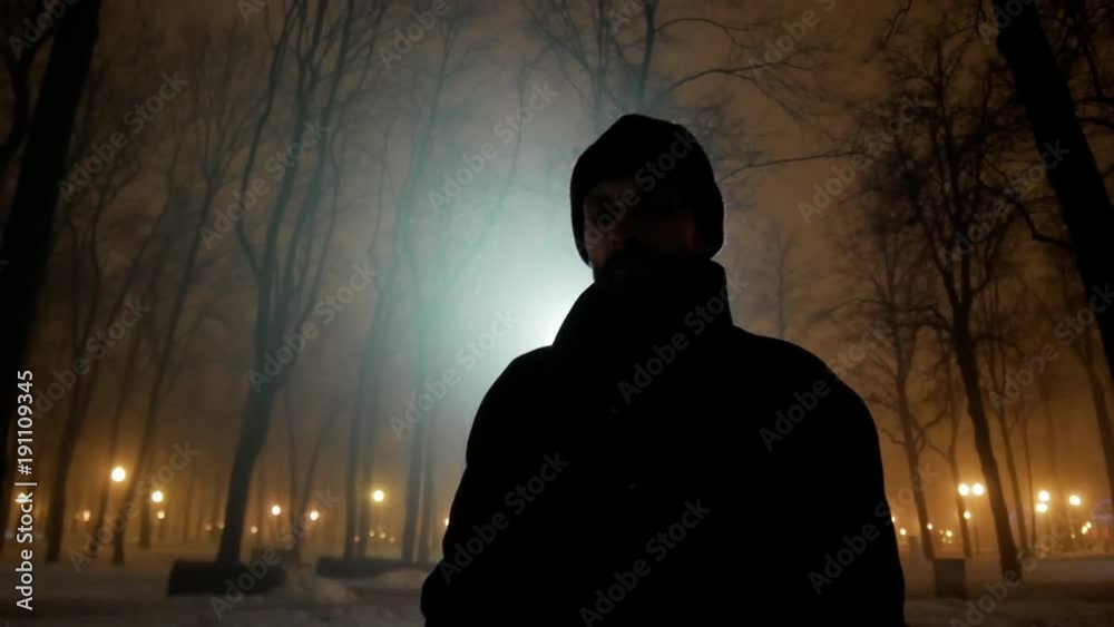 4k Black silhouette of man walks at dark winter night park with backlight close-up 4k Black silhouette of man walks at dark winter night park with backlight close-up