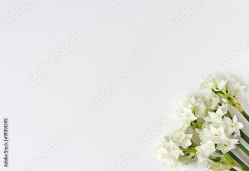 Spring styled stock photo. Easter concept. Feminine desktop scene with bouquet of narcissus, daffodil flowers on white table background. Empty space. Flat lay, top view.