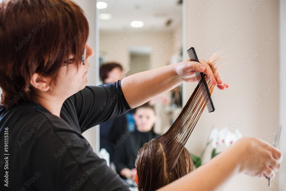 Fototapeta premium Stylist hairdresser doing haircut closeup of work equipment, the beauty industry