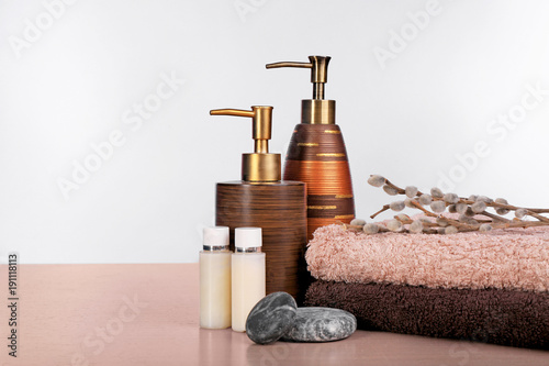 Set of fresh towels and toiletries on wooden table against white background