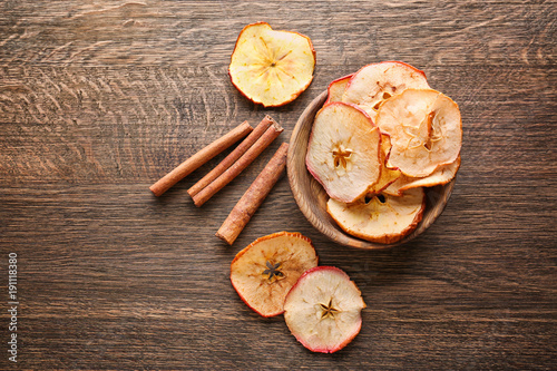 Composition with tasty apple chips and cinnamon on wooden background photo