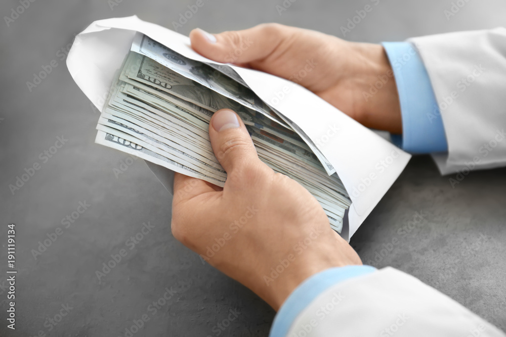 Fotografie Doctor with bribe at workplace, closeup