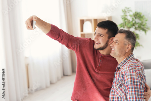 Young man taking selfie with his dad at home © Africa Studio