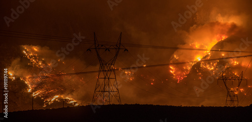 Fotografija Large wildfire in California on hillside behind silhouette of powerlines