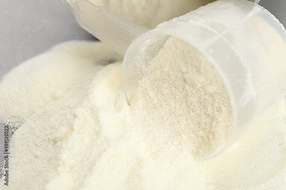 Protein powder and measuring scoop on table, closeup Protein powder and measuring scoop on table, closeup