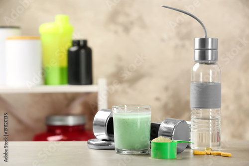 Composition with protein powder, shake and dumbbell on blurred background