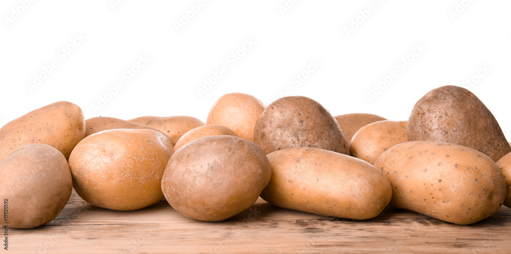 Fototapeta premium Fresh raw potatoes on wooden table against white background