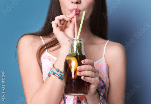 Young woman with tasty refreshing lemonade on color background