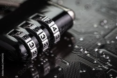 Digital cyber safety or security encryption concept, code numbers on combination pad lock on computer circuit board with solder, technology to encode online information or data protection
