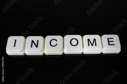 Income text word title caption label cover backdrop background. Alphabet letter toy blocks on black reflective background. White alphabetical letters.