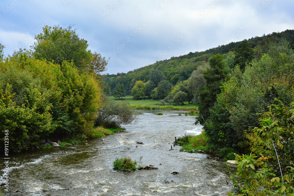 Countryside landscape with view of stormy river, slopes, glade and trees. Countryside landscape with view of stormy river, slopes, glade and trees.