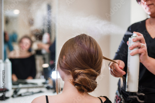 Hairdresser fixing woman hair with hairspray