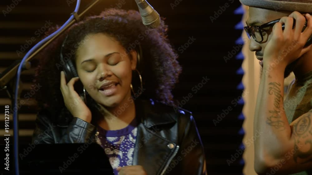 Female and male black singers recording in a studio Female and male black singers recording in a studio