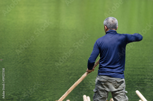 Asian Fisherman on the bamboo raft at big green swamp