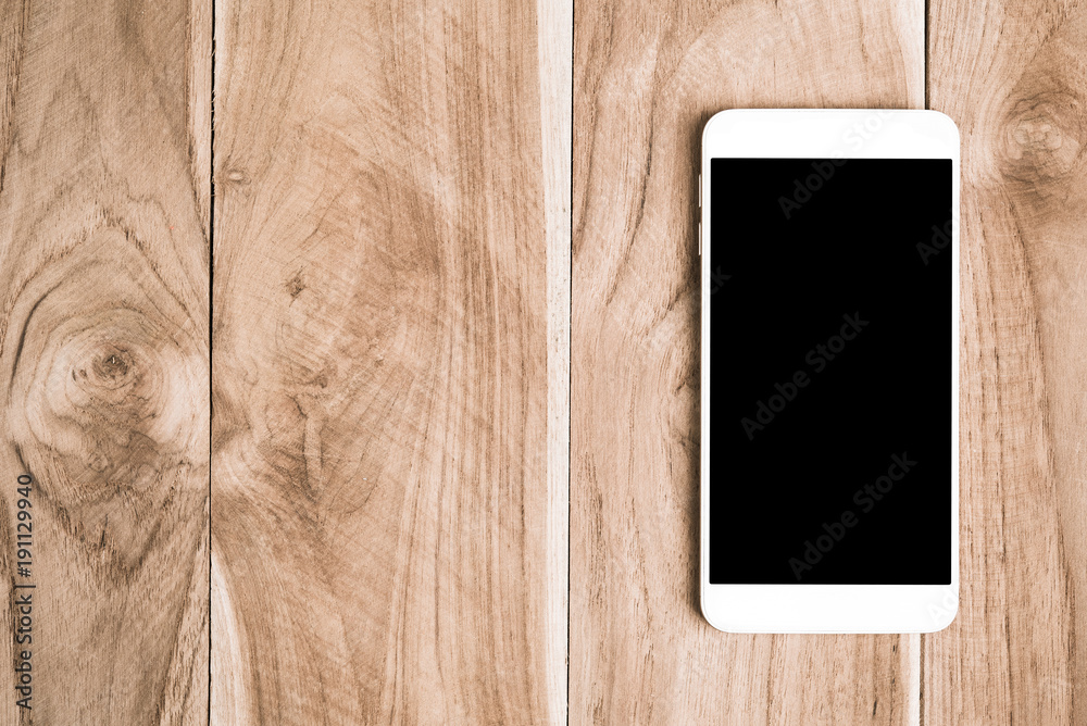White mobile smart phone with black blank screen on wooden desk technology concept design White mobile smart phone with black blank screen on wooden desk technology concept design