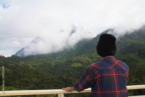 Asian young man in Scottish shirt and black hat hiking at mountain peak above clouds and fog Hiker outdoor. Doi Luang Chiang Dao Chiangmai Province,In morning. photo