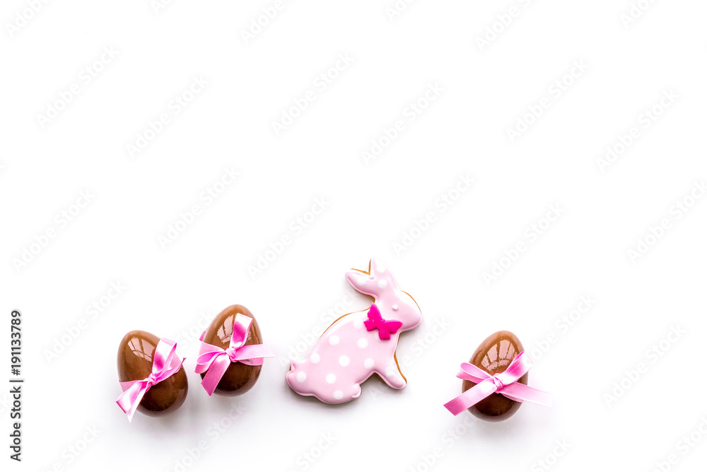 Sweets for Easter table. Chocolate eggs near cookies in shape of Easter bunny on white background top view copy space Sweets for Easter table. Chocolate eggs near cookies in shape of Easter bunny on white background top view copy space