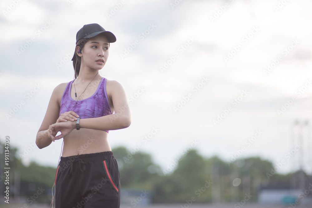 Smiling of Asia woman athlete sitting on an exercise mat and stretching in a field. Smiling of Asia woman athlete sitting on an exercise mat and stretching in a field.