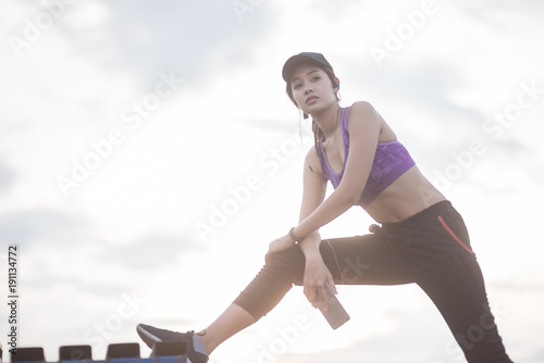 Smiling of Asia woman athlete sitting on an exercise mat and stretching in a field.