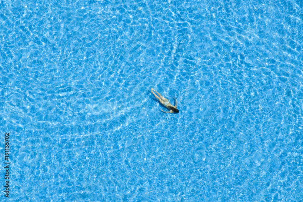 Girl swim in the swimming pool at the hotel. Top view Girl swim in the swimming pool at the hotel. Top view