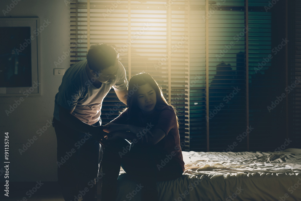 depressed Couple Husband and wife sitting head in hands on the bed in the dark bedroom with low light environment, dramatic concept