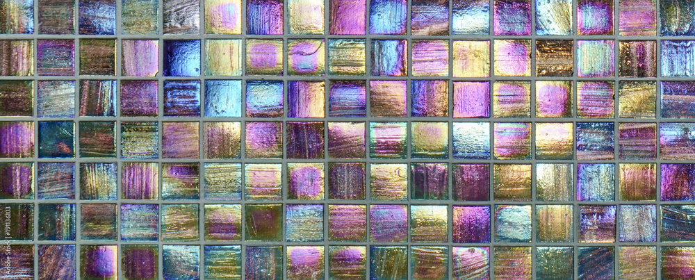 Colorful square metallic tiles on a wall or floor. Blue, green, teal, yellow, orange, purple reflective tile pattern. Shiny tile pattern with purple, teal, green, blue, yellow, gold and orange.