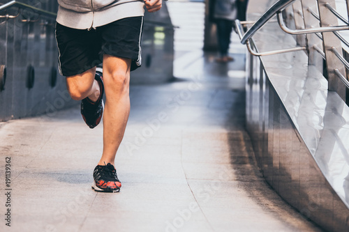 Close up of Young athletic man jogging on city bridge at the morning.
