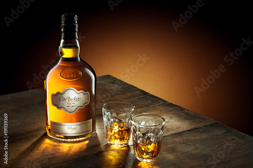 SELF MADE LABLE. NO LOGO. NO TRADEMARK.  view of glass of  whiskey and a bottle aside on color background. 