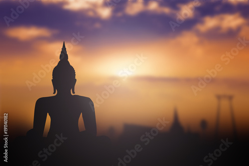Silhouette Buddha with blurred tourist attraction in thailand on golden sunset background. © Choat