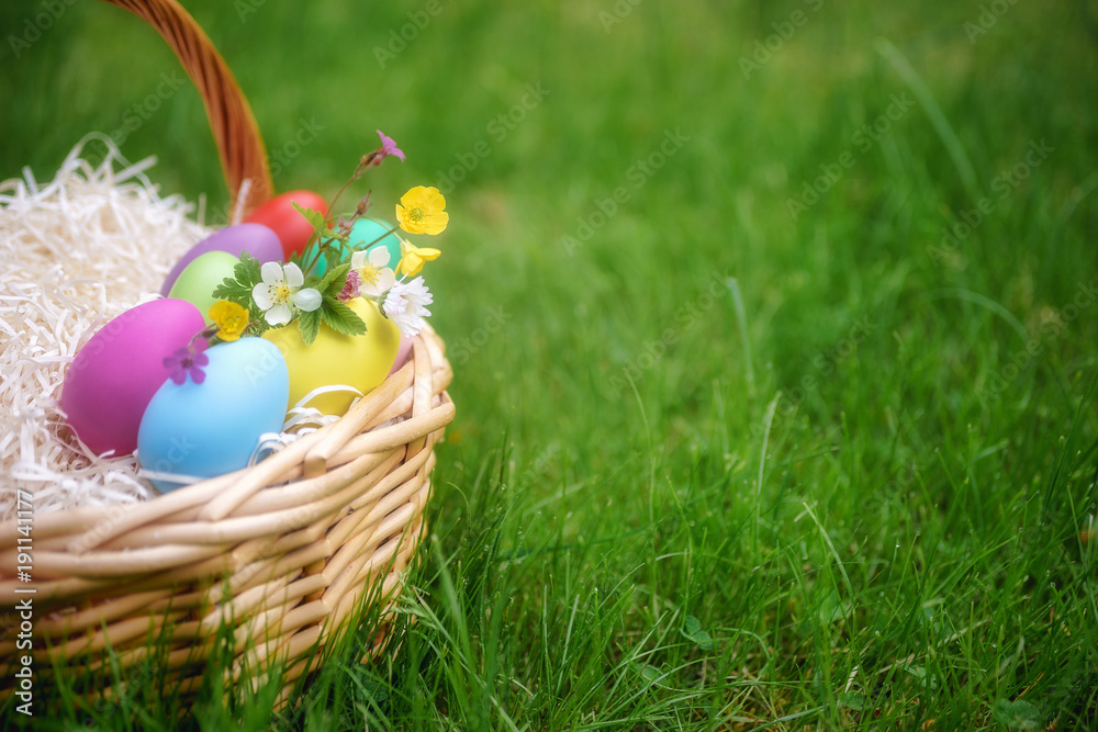Basket with colorful easter eggs on green springtime grass Basket with colorful easter eggs on green springtime grass