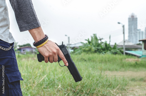 Killer holding a gun side him , cropped shot of man holding gun in hand.